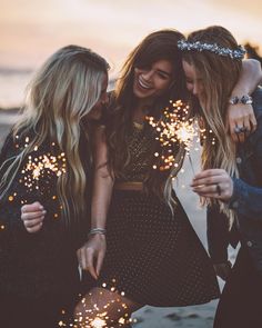 three girls are standing together and holding sparklers