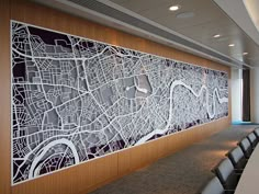 a large city map mounted to the side of a wall in a conference room with chairs around it