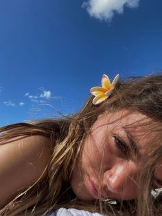 a woman with long hair and a flower in her hair is laying on the beach