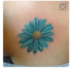 a woman's back with a blue flower tattoo on it