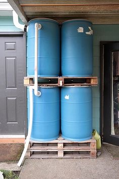 two large blue barrels stacked on top of each other in front of a building with a black door