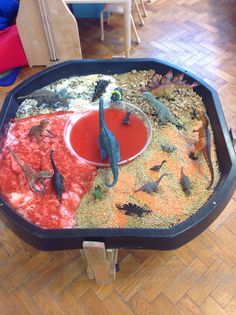 a table that has various types of dinosaurs in it and is filled with dirt, sand, and water