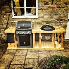 an outdoor kitchen made out of pallets and wooden planks with a grill on top