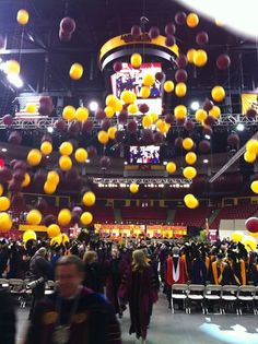 a large group of people standing in front of a basketball court filled with yellow balls