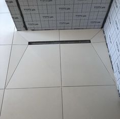 a bathroom with white tiles and black grouting on the floor, in front of a tiled wall