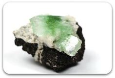 a piece of green and white rock sitting on top of a white surface