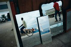 three pictures of a man riding a bike in front of a mirror with the reflection of another person on it