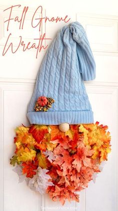 a blue knitted hat hanging on the side of a door with fall leaves around it