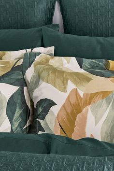 an image of a bed with green and yellow leaves on it's comforter