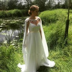 a woman in a white wedding dress standing next to a pond