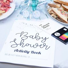 the baby shower activity book sits on a table with other foods and desserts around it