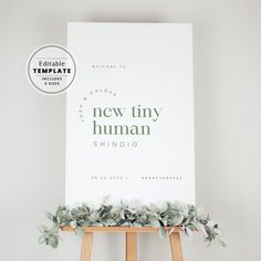 a white poster with the words new tiny human on it next to an easel