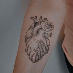 a tattoo on the arm of a woman with a heart and two hands holding a rose