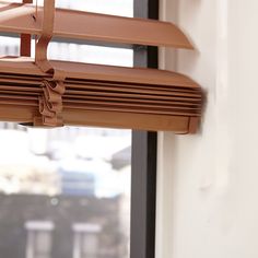 a close up of a window sill with the blinds pulled down and tied together