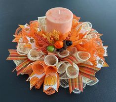 a candle is sitting on top of some orange ribbons and other decorative items that are arranged around it