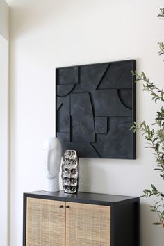 a white vase sitting on top of a wooden cabinet next to a black and white wall