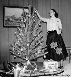 a woman standing next to a small christmas tree