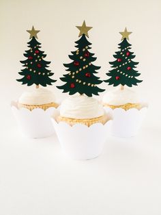 three cupcakes with frosting and christmas trees on top are sitting next to each other