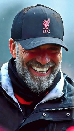 a man with a beard wearing a liverpool hat