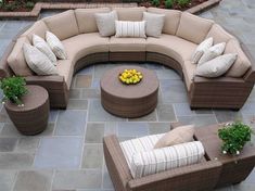 an outdoor sectional sofa with pillows on it and a coffee table in the middle, surrounded by brick pavers