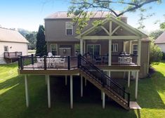 a house that is on the grass with stairs leading up to it's second story