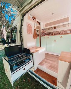 the interior of an rv with its door open and stove top oven in the back