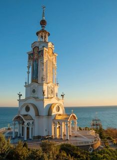 an old white church by the ocean on a sunny day