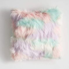 a multicolored faux fur pillow on a white background, with pastel hues