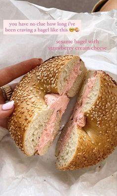 someone is holding a bagel with pink frosting on it and the sandwich has been cut in half