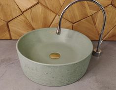 a green sink sitting on top of a counter next to a wooden wall with a metal faucet