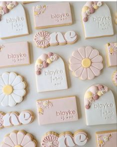 decorated cookies are arranged on a white surface with flowers and name tags that spell out the word blvde