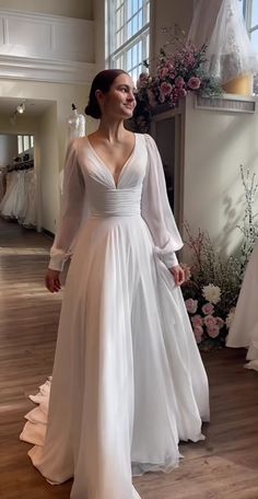 a woman in a white wedding dress standing on a wooden floor next to a window