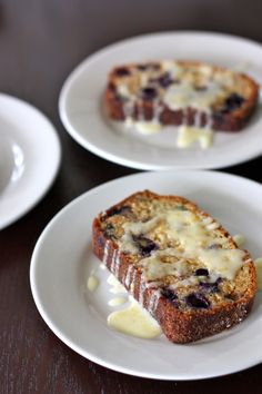 two white plates topped with slices of bread covered in blueberry sauce and melted cheese