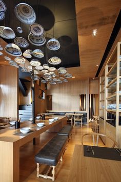 a long table with plates hanging from it's ceiling in a room that has wooden floors and walls