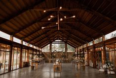 the inside of a large wooden building with tables and chairs set up for an event