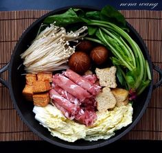 a pan filled with meat and vegetables on top of a mat