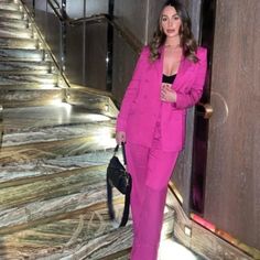 a woman in a pink suit is standing on the stairs