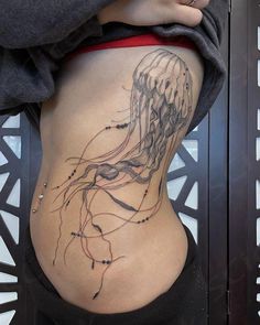 a woman's stomach with a jellyfish tattoo on it