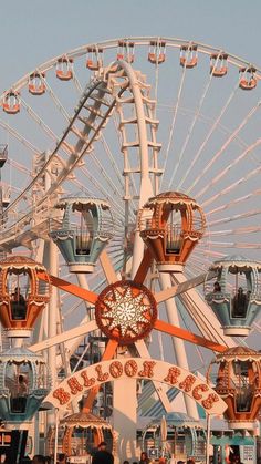 an amusement park ferris wheel with people standing around it