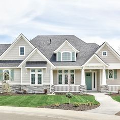 a large gray house with white trim on the front and side windows, grass in front