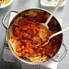 a pan filled with spaghetti and meat on top of a table