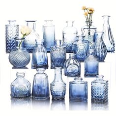 a collection of blue glass vases with flowers in the middle one on each side