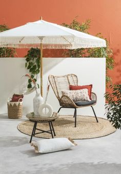 an outdoor area with wicker furniture and plants on the ground, including a white umbrella