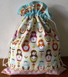 a drawstring bag with colorful owls on it sitting on top of a wooden table