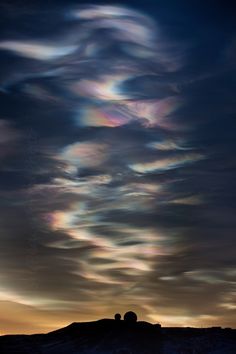 the sky is filled with swirly clouds and there are two people sitting on a hill