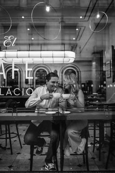 a man and woman sitting at a table in front of a restaurant