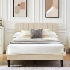 a white bed sitting in a bedroom next to two framed pictures