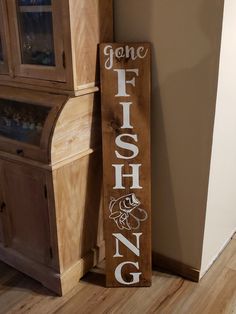 a wooden sign that says gone fishing on it next to a cabinet and cupboard