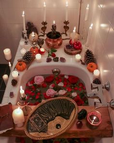 a bathtub filled with candles and flowers on top of a wooden table next to other items