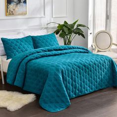 a bed covered in a teal quilted bedspread